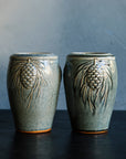 Two glossy, deep green Balsam Pinecone vases against a dark grey, lime-washed wall.