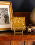 Decorative Old Detroit tiles in glossy Honey glaze on a handcrafted Stickley cabinet next to a stack of books and framed photo.