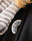 The Feather Pin is a small, light design. The feather is gently curved with straight barbs at the top and softer, wispier barbs near the bottom.