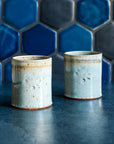 Two ceramic Rocks Cups in a glossy Frost glaze against a blue tiled backsplash.