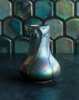Matte Green Iridescent Snowdrop vase on a dark slate foreground and green, tilled background.
