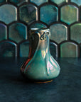 Matte Green Iridescent Snowdrop vase on a dark slate foreground and green, tilled background.