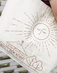 This cream tote bag's design is in a metallic copper color.