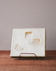 The back of the tile has a divot in the clay making is possible to hang it from a nail. There is also a stamp from the maker saying "Weaver Tile Scott Weaver Horton, MI".