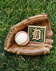 Baseball glove with a baseball and a 4x4 Old English D tile in Ivy/Natural on grass.
