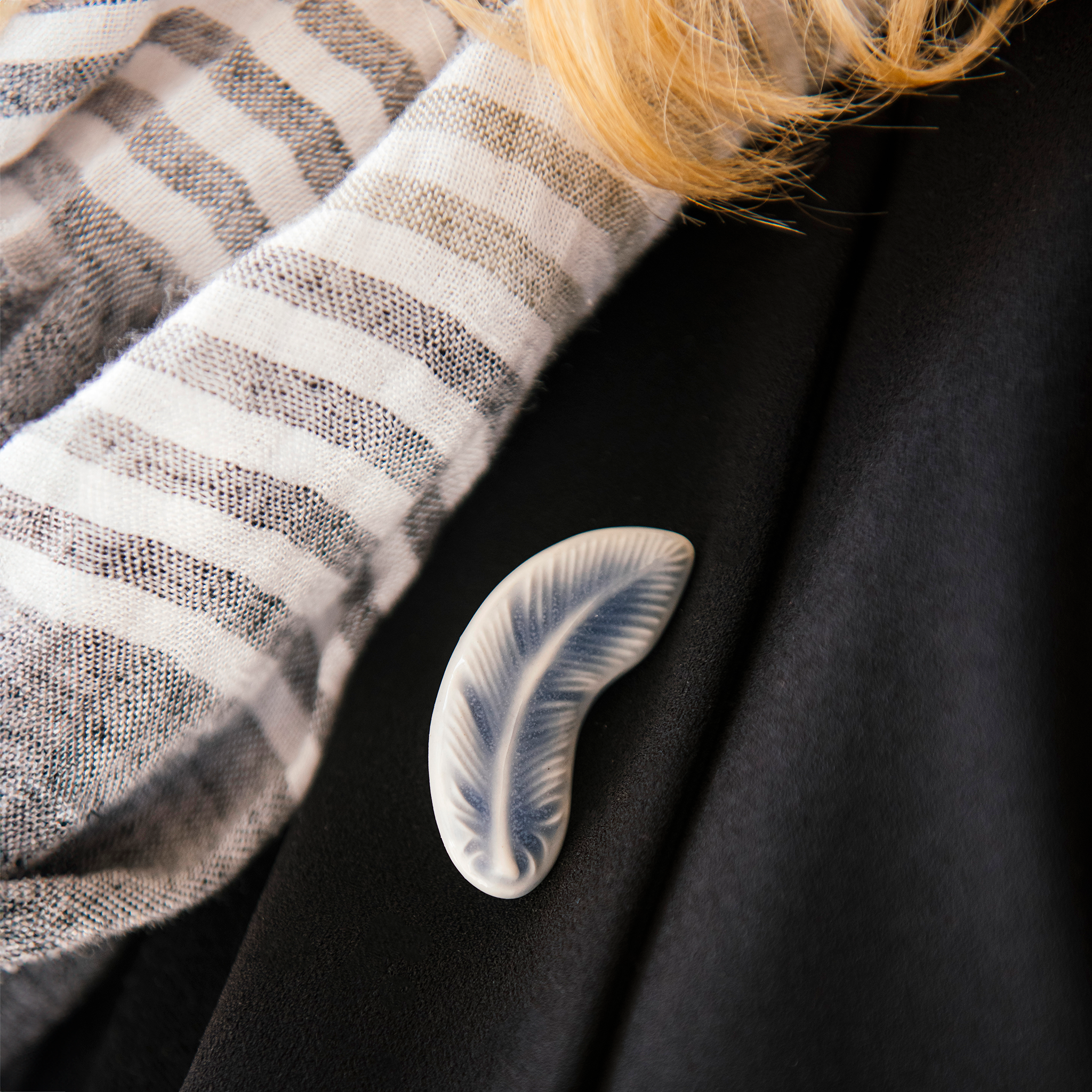 The Feather Pin is a small, light design. The feather is gently curved with straight barbs at the top and softer, wispier barbs near the bottom.