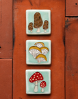 Hand-painted Morel, Oyster and Amanita mushroom tiles stacked vertically on deep, terracotta colored roof tiles. 