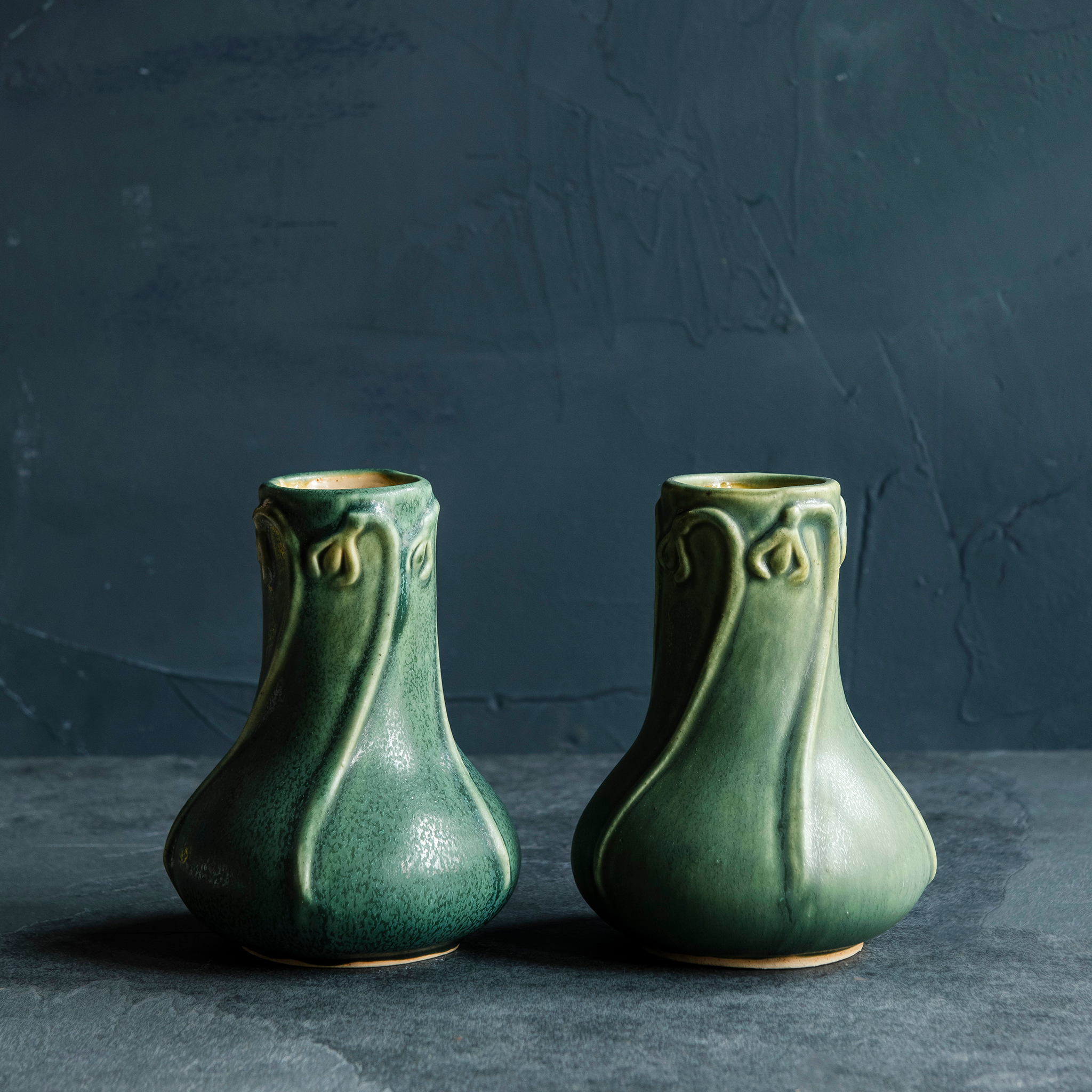 Elm-glazed Snowdrop Vase with snowdrop flower carvings on a dark, textured background and slate foreground.