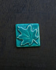 The Pewabic blue glazed maple leaf tile is featured. This tile is a matte turquoise blue.