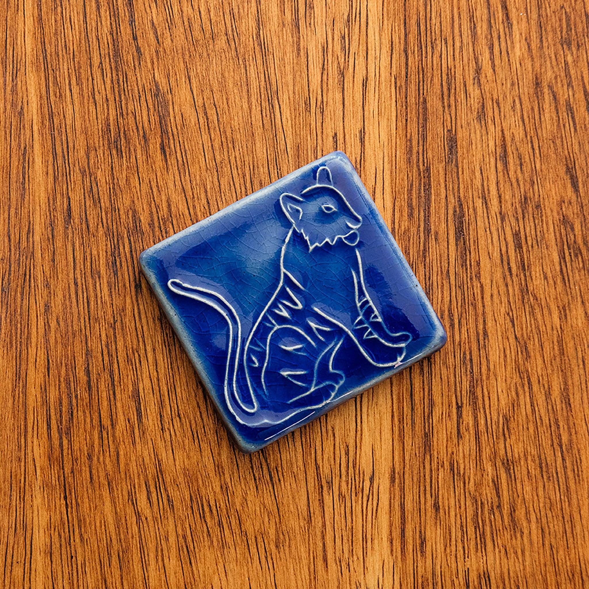 Glossy blue 3x3 Tigers Tile on a warm, wooden background.