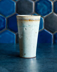 A ceramic Pewabic Pint in a glossy Frost glaze against a blue hex tile background. 