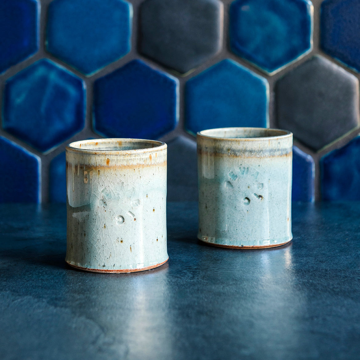 Two ceramic Rocks Cups in a glossy Frost glaze against a blue tiled backsplash.