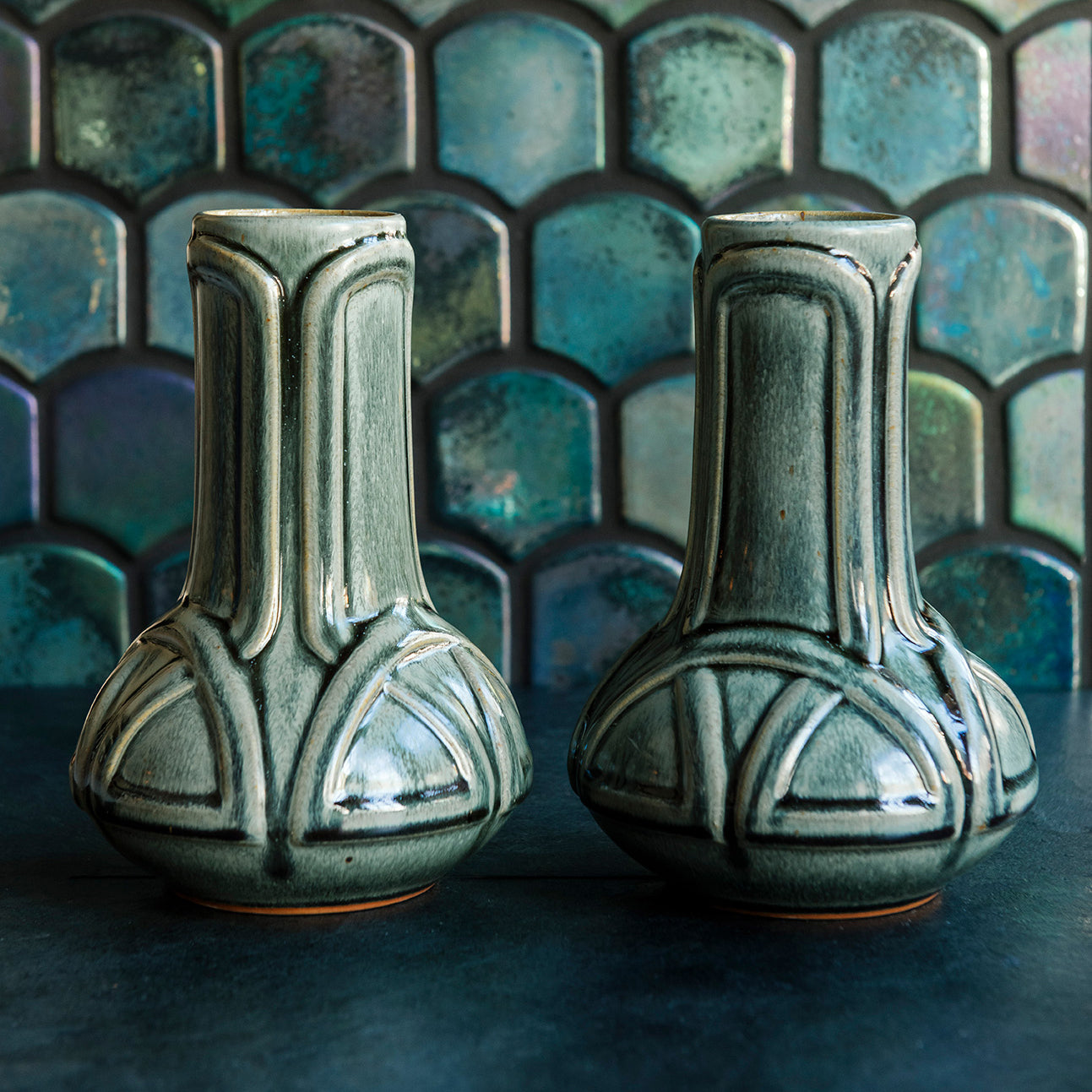 Two green Balsam Celtic Vases against an Iridescent fishscale tile background. 