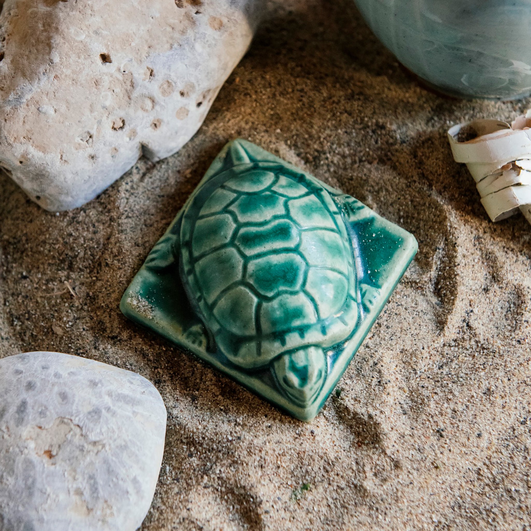 This thick high relief paperweight has the shape of a small turtle. It has detailed feet, face, and shell and sits on a square base.