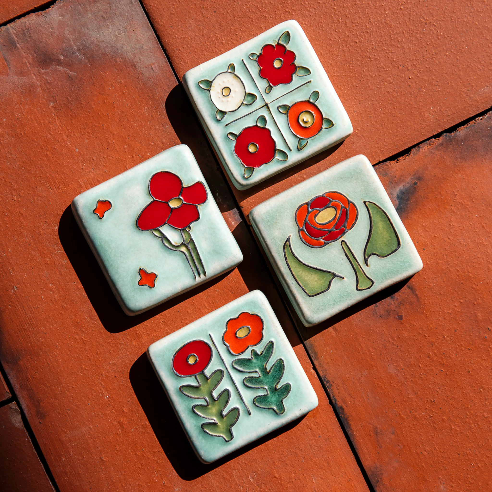 The Four Flowers Tile is on a bright red brick background with the other tiles in the Poppy color palette - the Rose Tile, the Two Flowers Tile and the Cactus Flower Tile.