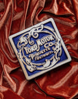 Ford Motor Co. Piquette logo tile on an orange velveteen fabric background. 