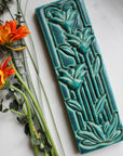 The Floral Tile features the matte turquoise Pewabic Blue glaze.