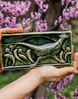 This hand-sculpted tile features a pheasant running through a field of dandelions. It is featured in a glossy green Kale glaze. 