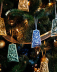 Various bell-shaped ceramic ornaments are hung on a lit Christmas tree.