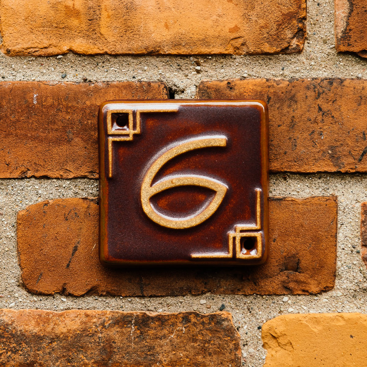 The Craftsman style ceramic 6 address number is in the satin reddish brown Carmine glaze option.